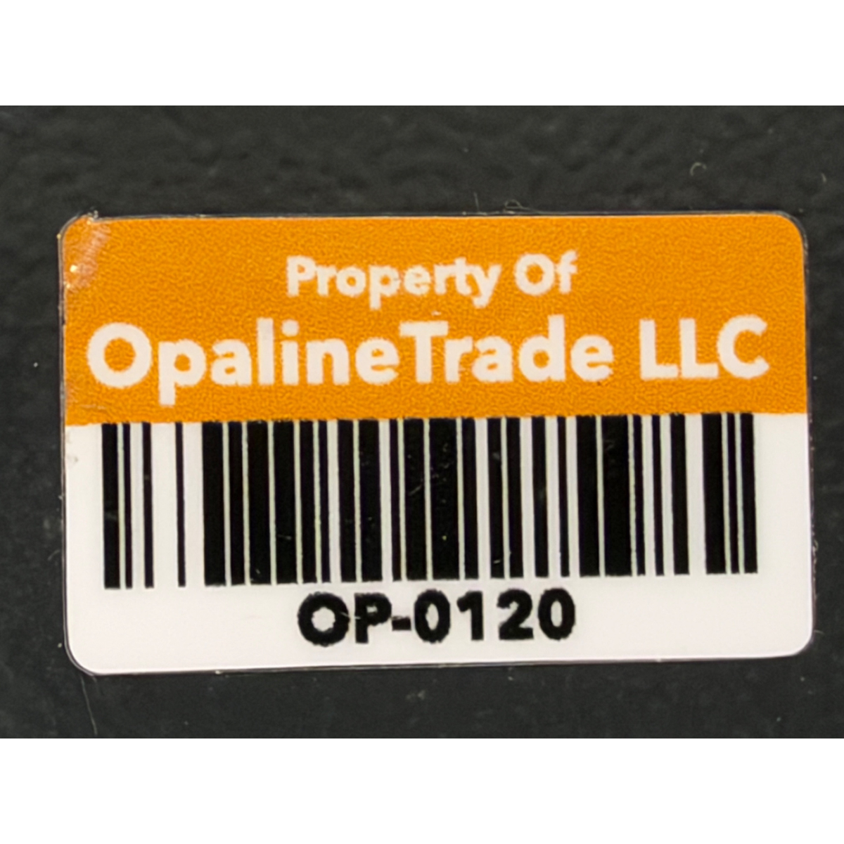  Close-up view of an asset tag label reading 'Property Of OpalineTrade LLC' with barcode OP-0120.
