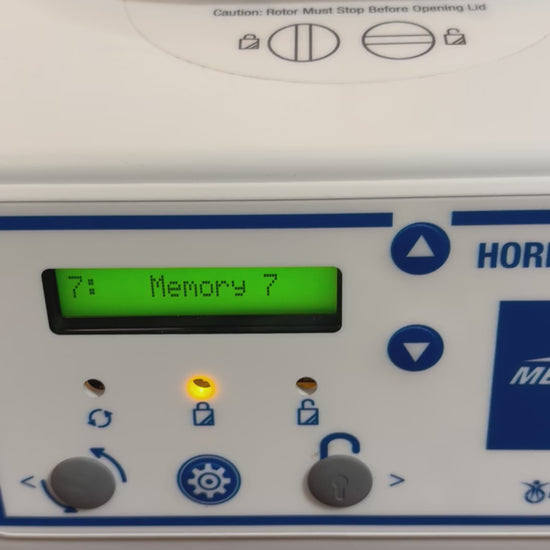 A video demonstration of the Drucker Diagnostics Horizon 6 Flex centrifuge in operation. A gloved hand presses a button on the control panel, changing the digital display from "Memory 7" to a 1-minute cycle at "3500 RPM". As the cycle begins, the lid lock engages (indicated by a lighted lock icon) and the internal chamber illuminates with bright blue LED lighting. The camera looks down through the clear lid at the spinning rotor before panning back to the control panel, where the display toggles between "17