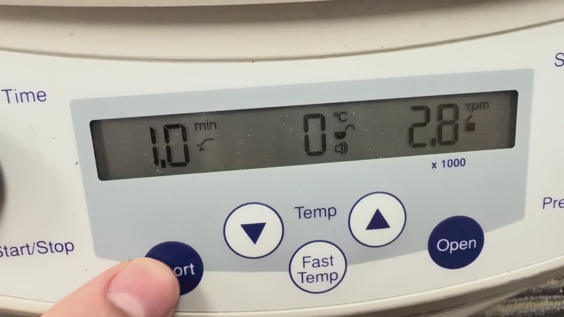 Video showing a close-up of the Eppendorf 5415 R digital control panel in operation. A finger presses and holds the "Short" spin button, while the LCD screen displays the timer counting up in seconds, a temperature reading of 2°C, and the speed accelerating to 2,800 RPM before decelerating when the button is released.